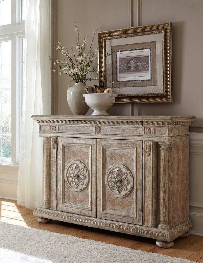 an ornately decorated cabinet in front of a window with vases and flowers on top