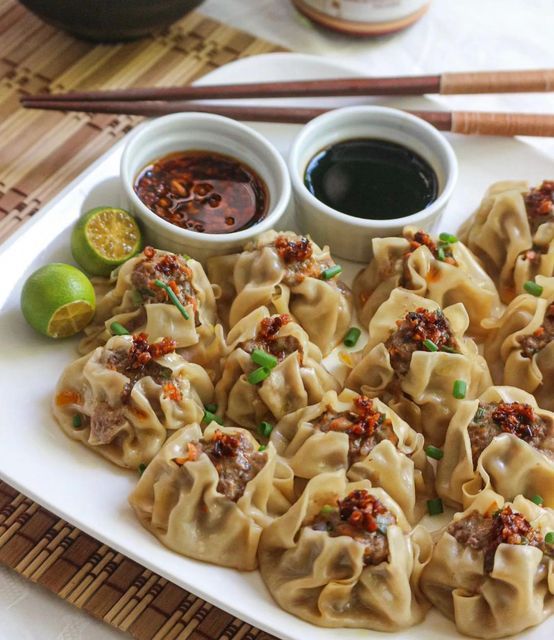 some dumplings are sitting on a plate with dipping sauces