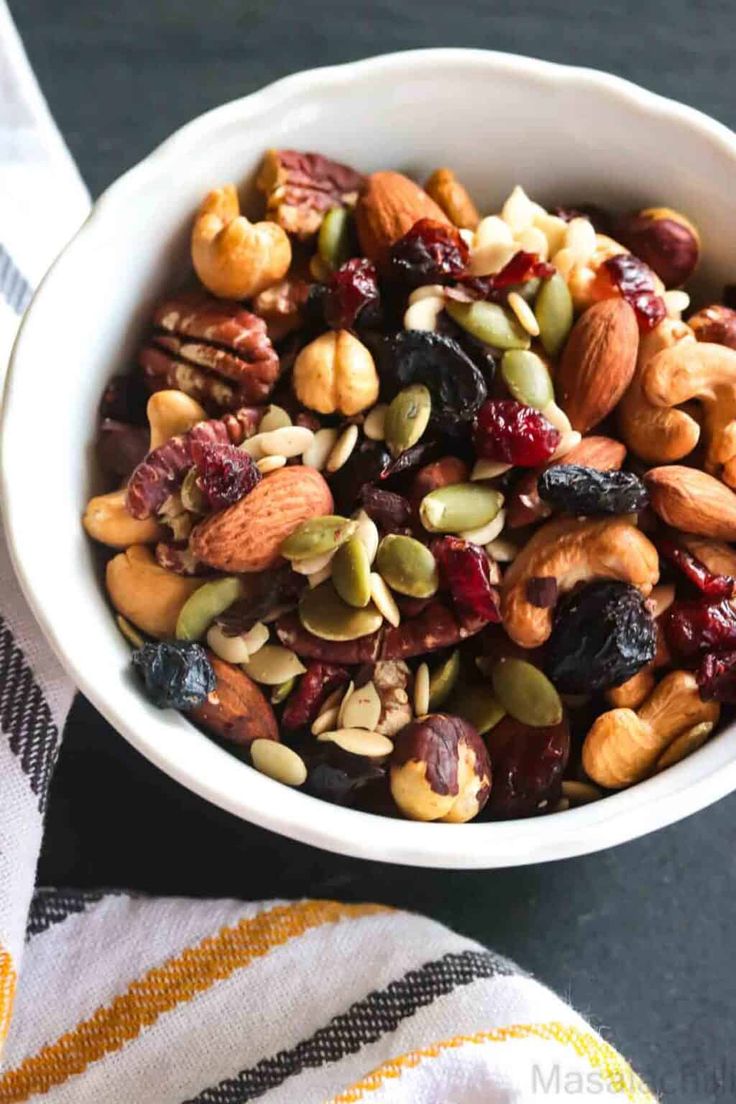 a white bowl filled with nuts and raisins