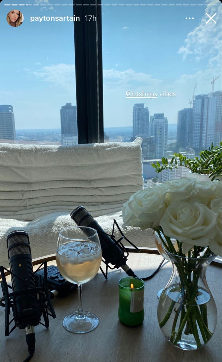 a glass of wine and some flowers on a wooden table in front of a window