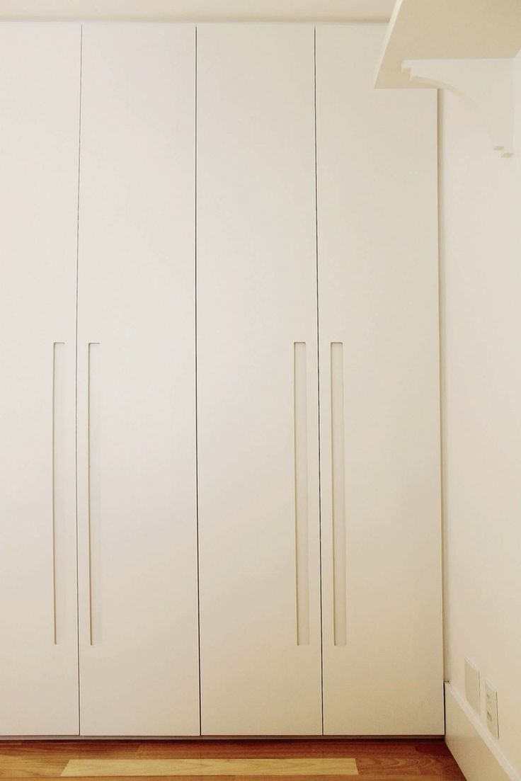 an empty room with white cupboards and wood flooring on the side walk in closet