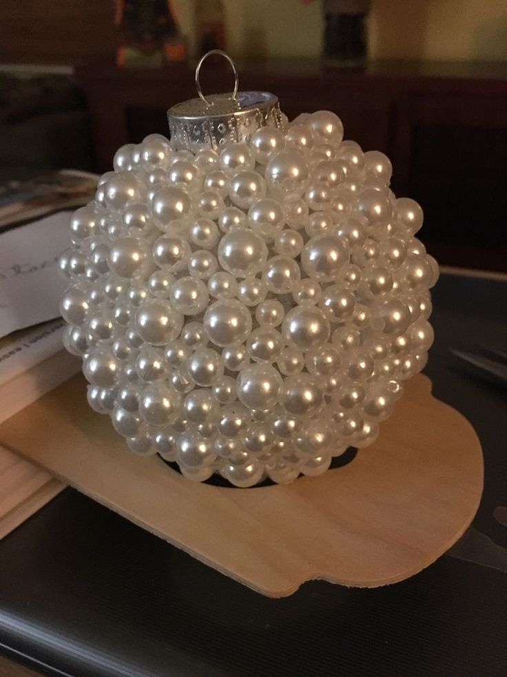 a white beaded ball sitting on top of a wooden tray