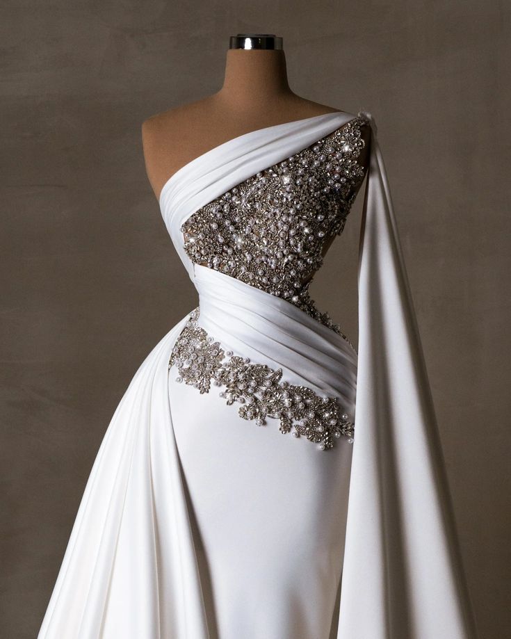 a white wedding dress with silver beading on the shoulders and neckline, draped over a mannequin