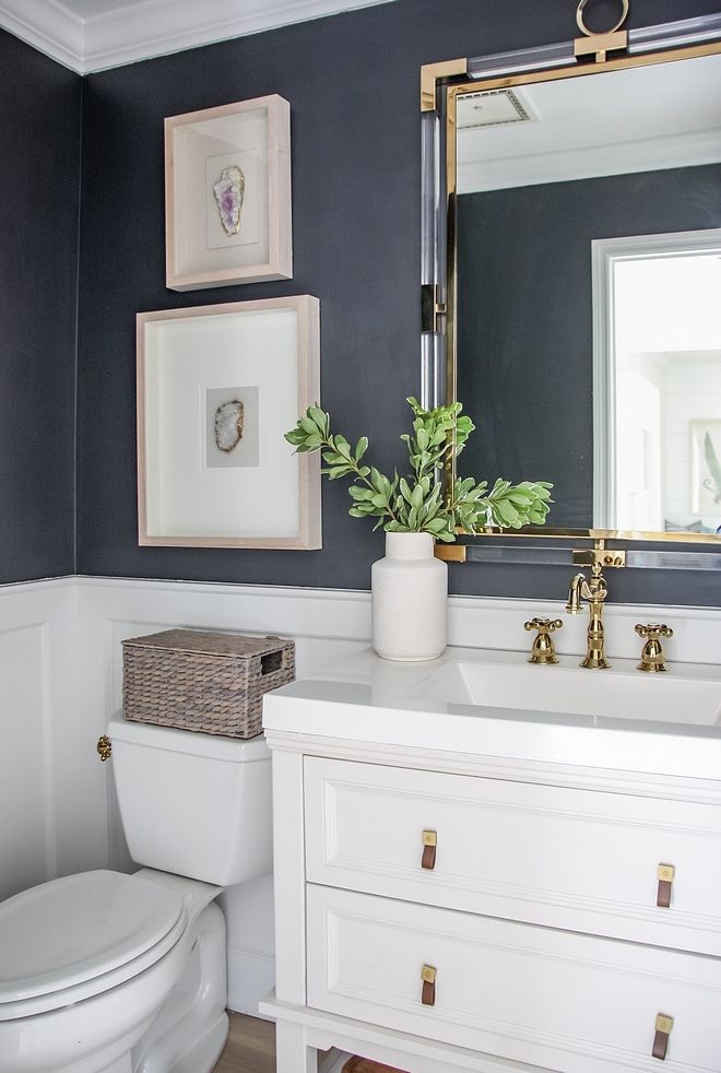 a white toilet sitting under a bathroom mirror next to a sink and a potted plant