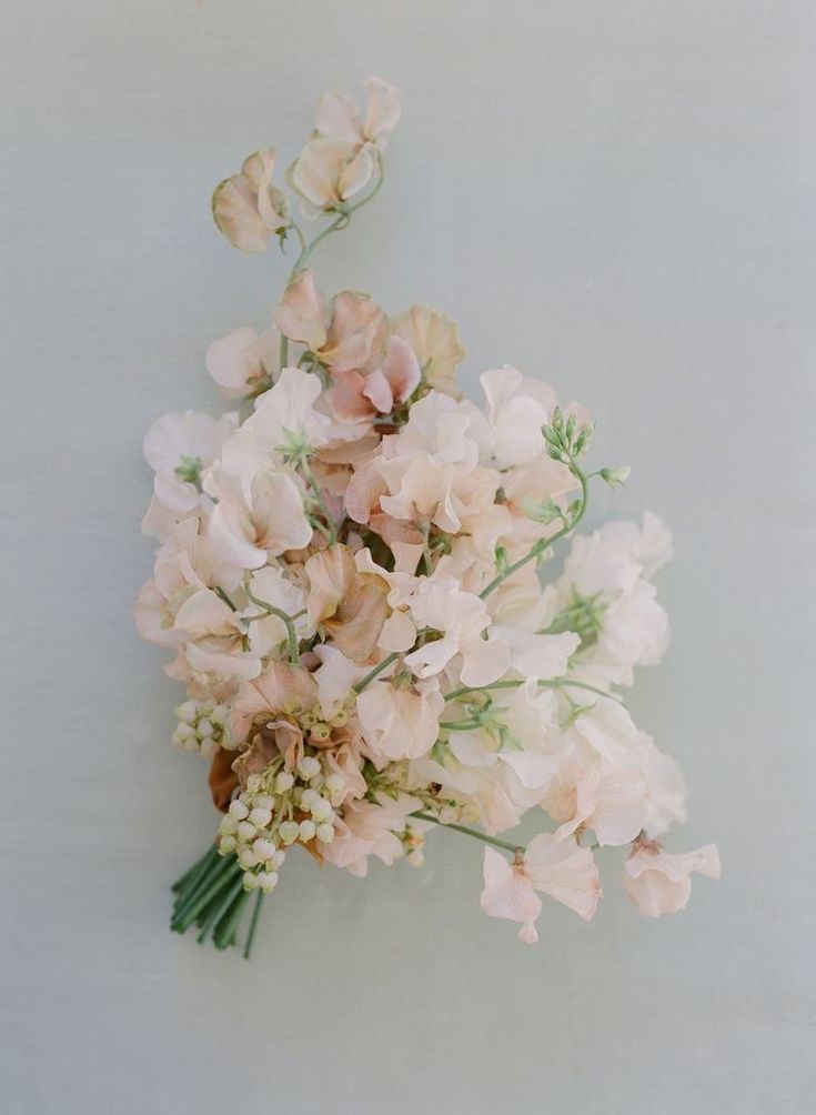 a bouquet of pink flowers sitting on top of a white wall next to a window