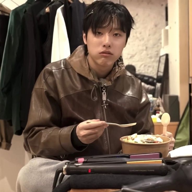 a man sitting at a table with a bowl of food in front of his face