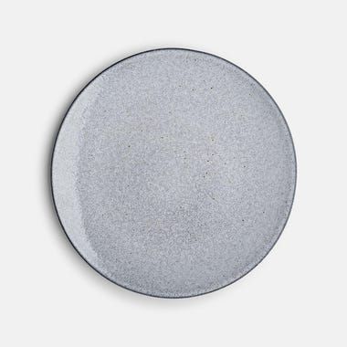 a white plate with grey speckles on the rim is shown in front of a gray background