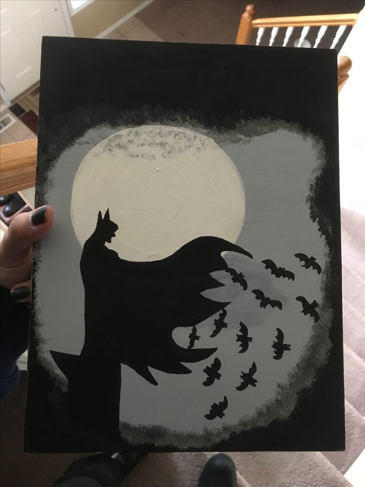 a person holding up a painting with bats on it