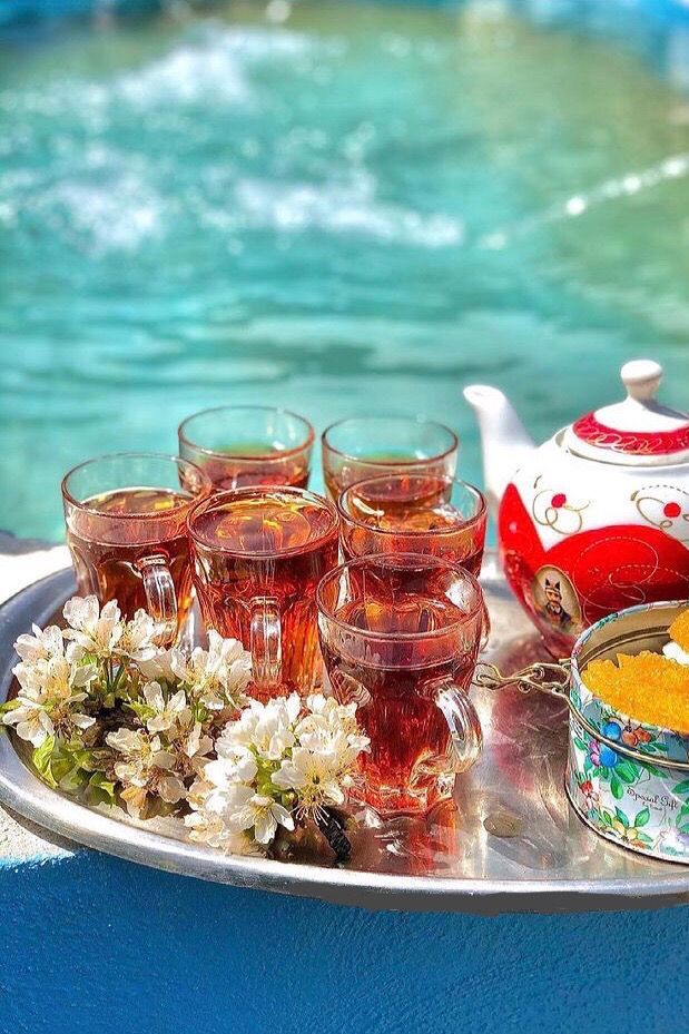 a tray with glasses and tea next to a pool