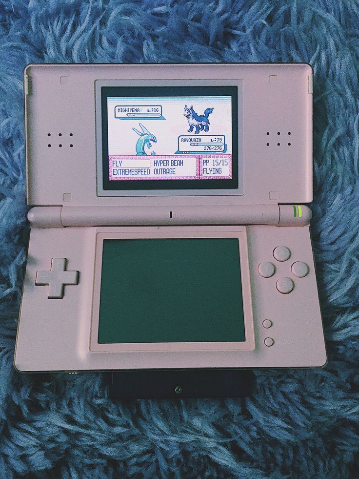 an old nintendo gameboy sitting on top of a blue blanket with the screen turned off