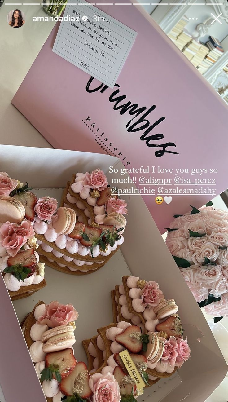 a box filled with lots of cupcakes covered in frosting and pink flowers