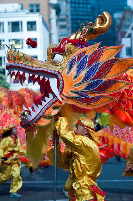 some people in costumes are walking down the street with dragon heads on their head and arms