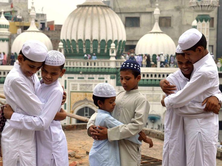 a group of young children standing next to each other in front of a white building