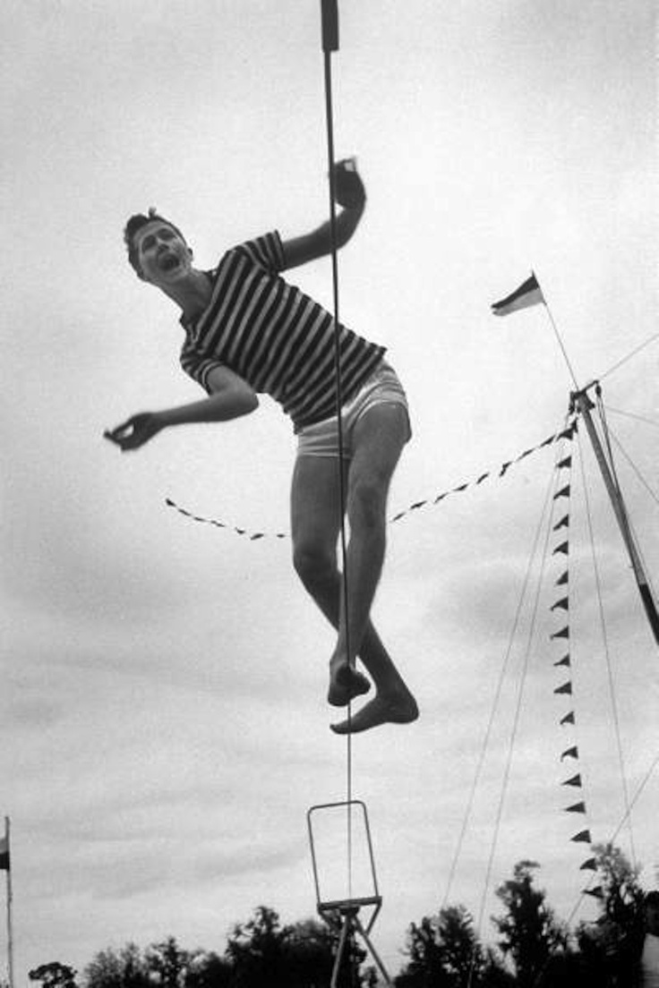 an old photo of a man on a pole in the air with his hands up