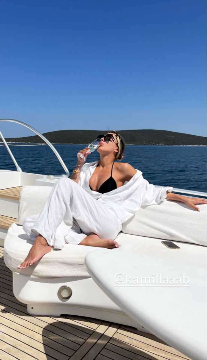 a woman sitting on the back of a boat drinking water