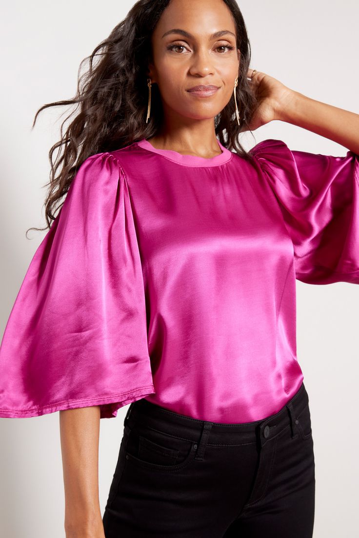 Make a chic statement in this gorgeous satin top by Nation LTD, designed with a flowy fit, voluminous bell sleeves, and a rib knit collar. Wear it tucked into jeans or trousers, or pair with coated denim for a little edge. Satin Puff Sleeve Tops For Work, Chic Bell Sleeve Top With Blouson Sleeves, Chic Tops With Blouson Bell Sleeves, Chic Blouson Bell Sleeve Tops, Glamorous Spring Blouse With Blouson Sleeves, Chic Bell Sleeve Stretch Tops, Spring Puff Sleeve Top With Blouson Sleeves, Spring Stretch Puff Sleeve Top With Blouson Sleeves, Glamorous Fall Blouse With Blouson Sleeves