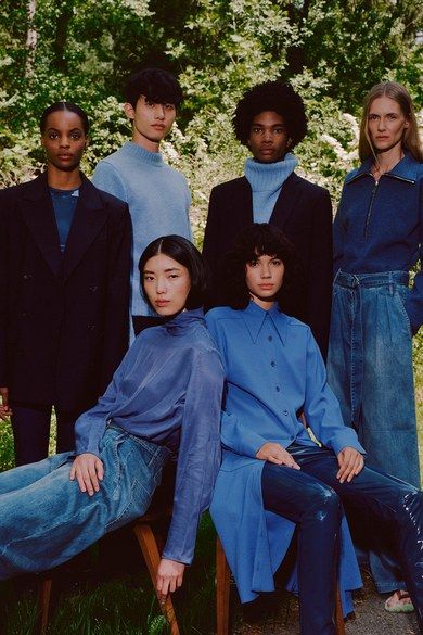 a group of people sitting next to each other in front of some trees and bushes