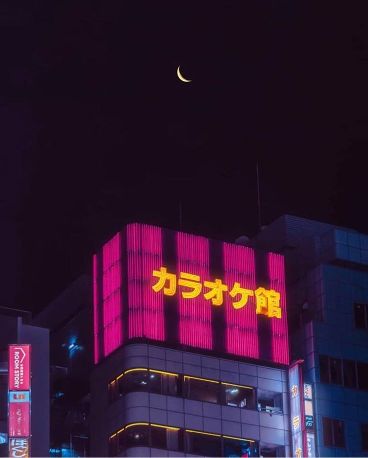 the moon is shining brightly in the night sky over a building with japanese writing on it