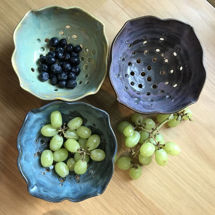 three bowls with grapes in them sitting on a table