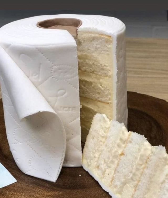 two pieces of cake sitting on top of a wooden plate next to a roll of toilet paper