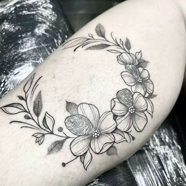 a woman's thigh with flowers and leaves tattooed on the side of her leg