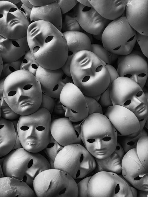 many white masks with faces are stacked together