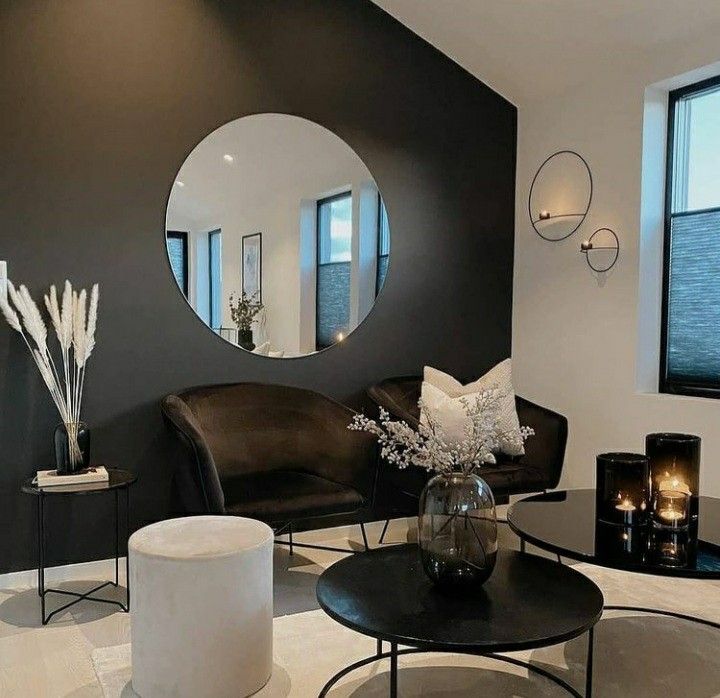 a black and white living room with round mirrors on the wall, leather furniture and candles