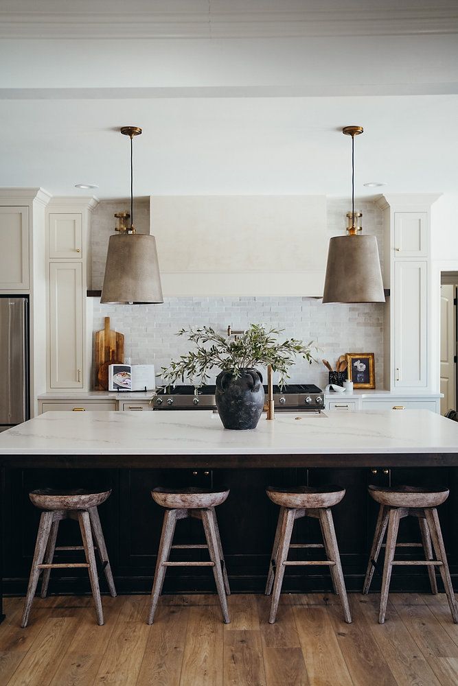 a large kitchen island with stools in front of it and lights hanging from the ceiling