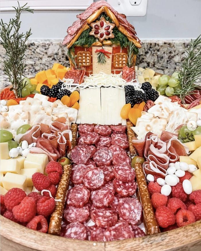 a platter filled with different types of cheeses and fruit on top of a table