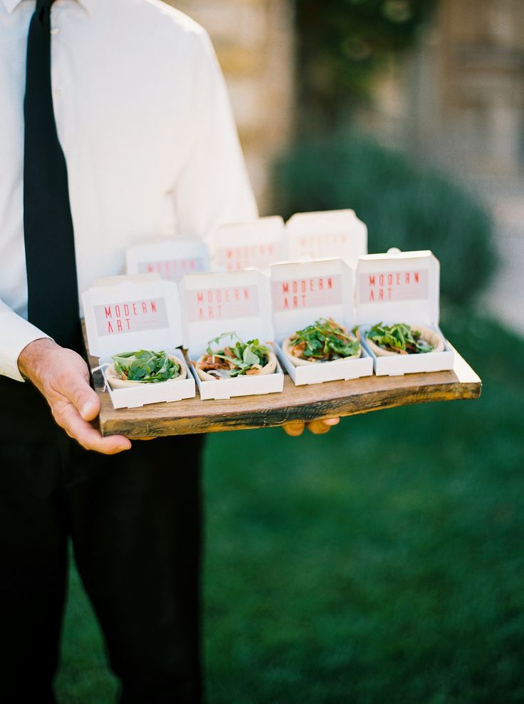 a man in a tie holding a tray with small food items on top of it