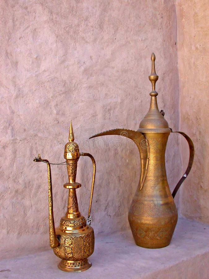 an old brass coffee pot and teapot are on display in front of a stucco wall