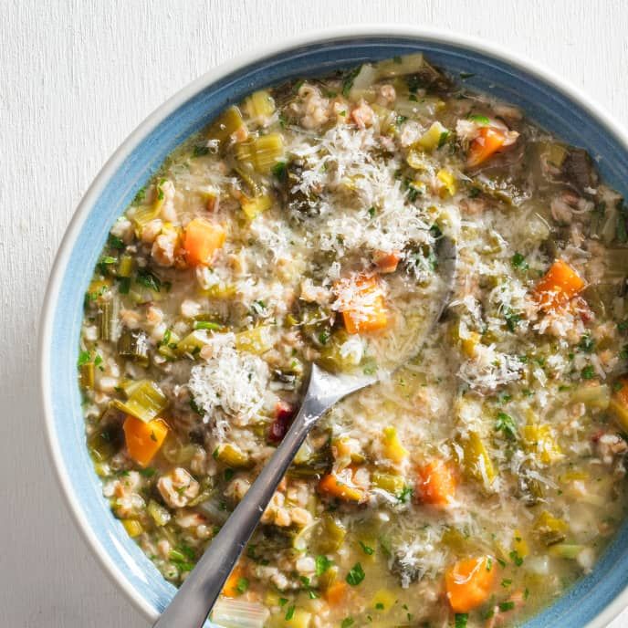 a bowl of soup with carrots, celery and parmesan cheese