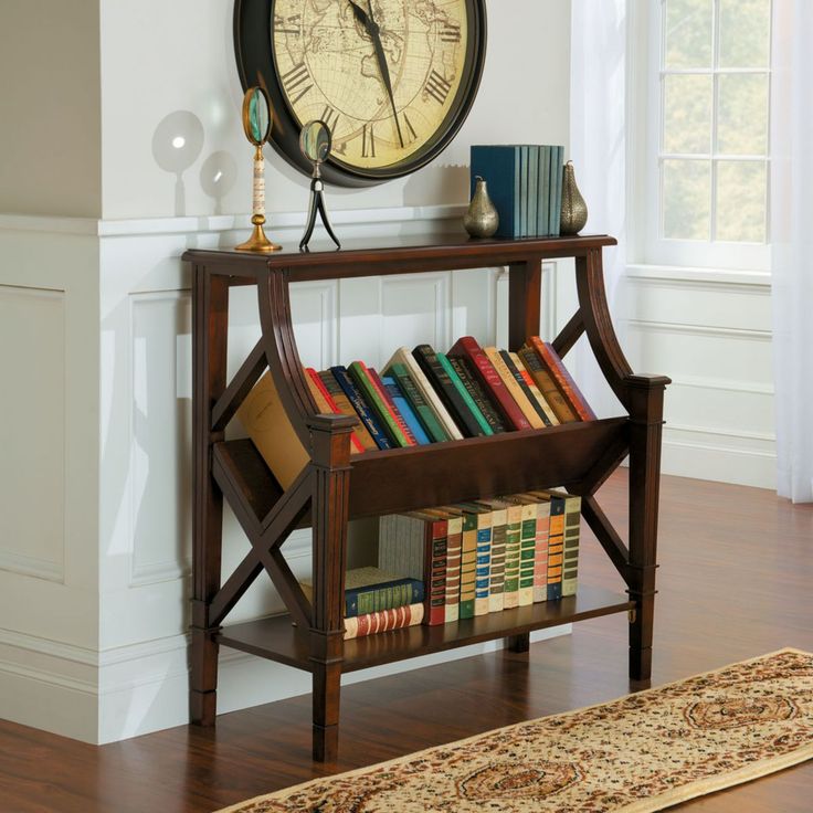 there is a clock on the wall above a book shelf with books in front of it