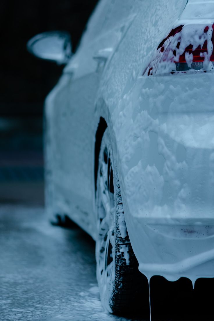 the back end of a white car covered in snow