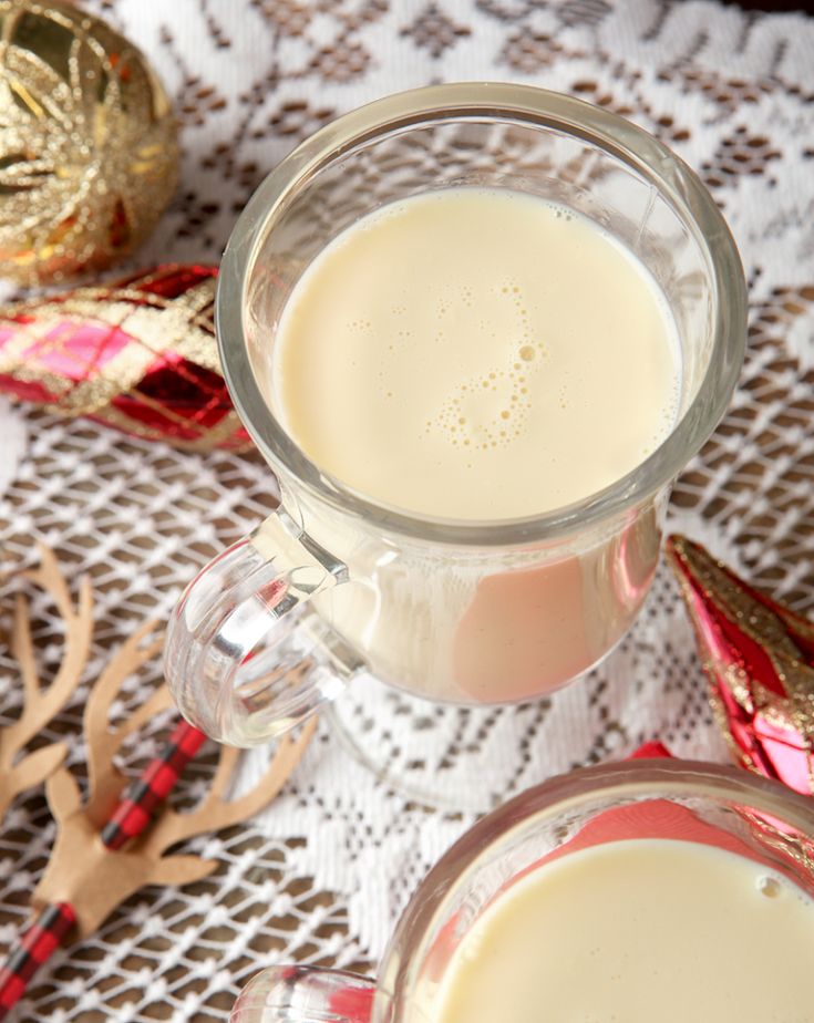 two glasses filled with liquid sitting on top of a table next to gold ornaments and napkins