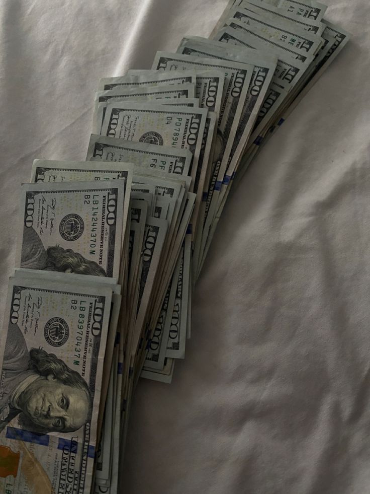 five stacks of twenty dollar bills laying on top of each other in front of a white sheet