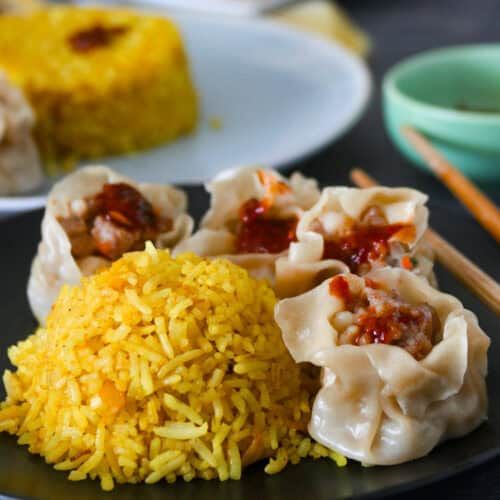 dumplings and rice on a plate with chopsticks