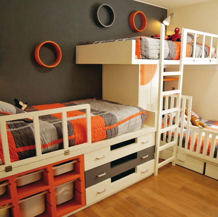 two bunk beds with orange and grey decor in a room that has wood flooring