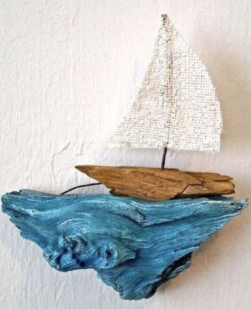 a small wooden sailboat floating on top of a blue ocean next to a white wall