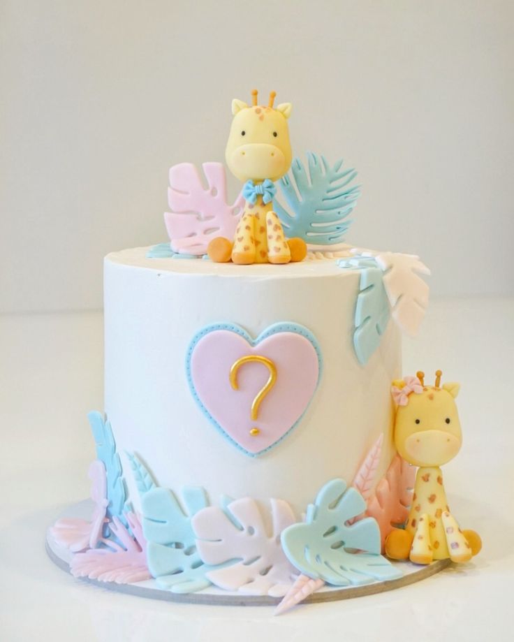 a cake decorated with giraffes, leaves and a heart on the top