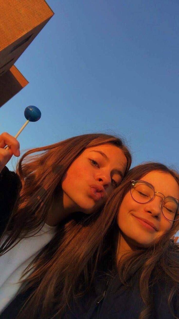 two young women standing next to each other holding lollipops in their hands