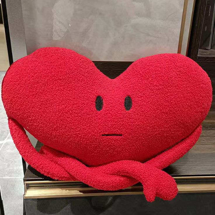 a red heart shaped pillow sitting on top of a counter