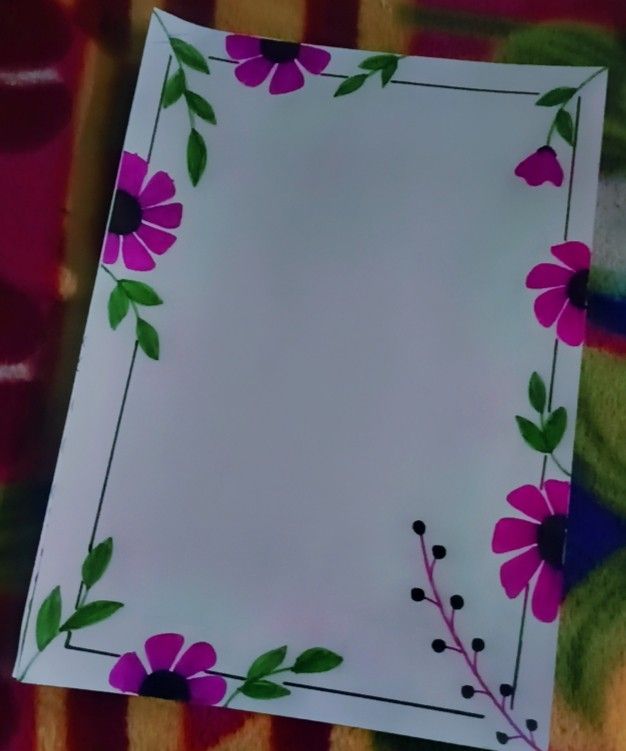 a paper with flowers painted on it sitting on a tablecloth covered floor next to a wall