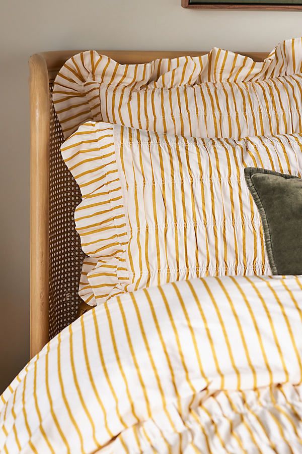 a bed with yellow and white striped comforter next to a painting on the wall