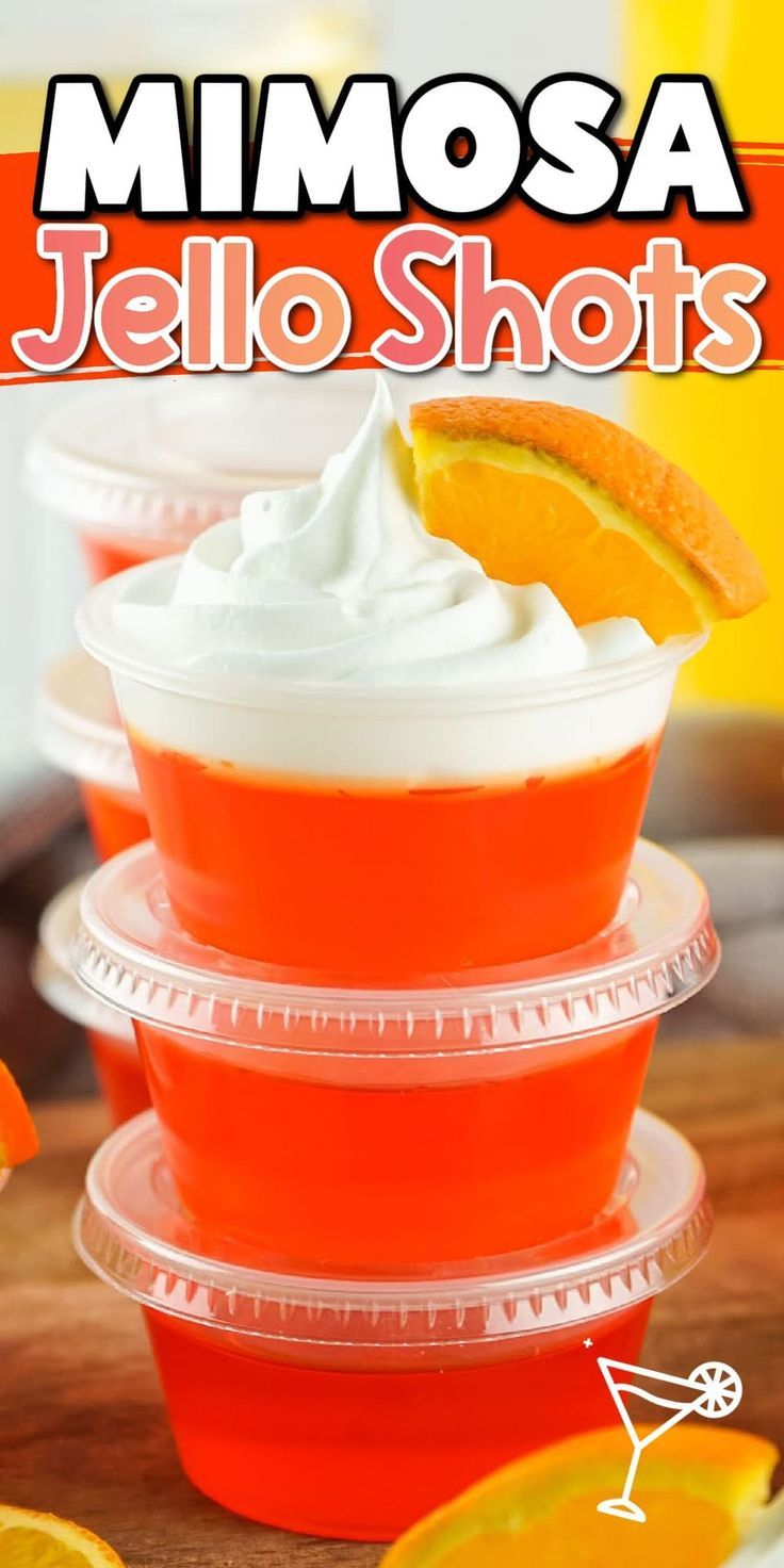 three cups filled with jello shots on top of a wooden table next to sliced oranges