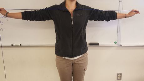 a woman standing in front of a whiteboard with her arms stretched out to the side