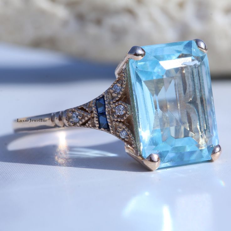 Sky Blue Topaz Engagement Ring/ 6 CT Blue Topaz Emerald Cut Diamond Wedding Ring/ Split Shank Milgrain Ring In 14K Gold/ Blue Sapphire Ring 𝐃𝐞𝐬𝐜𝐫𝐢𝐩𝐭𝐢𝐨𝐧 𝐨𝐟 𝐑𝐢𝐧𝐠 👉 Main Stone Material:- Lab Diamond 👉 Main Stone Shape:- Emerald Cut ( Blue Topaz ) 👉 Main Stone Carat Weight:- 6.00 CT ( Approx ) 👉 Main Stone Measurement:- 12x10 MM 👉 Side Stone:- Lab Diamond 👉 All Stone Clarity:- VVS 👉 Stone Luster:- Excellent 👉 Stone Make:- High Quality ● 𝐌𝐞𝐭𝐚𝐥 𝐃𝐞𝐭𝐚𝐢𝐥𝐬 👉 Metal Typ Anniversary Turquoise Topaz Ring With Gemstone Accents, Turquoise Topaz Ring With Gemstone Accents For Anniversary, Blue Birthstone Ring With Accent Stones For Anniversary, Turquoise Topaz Ring With Accent Stones For Anniversary, Heirloom Blue Sapphire Ring With Diamond Accents, Turquoise Sapphire Ring For Anniversary, Blue Birthstone Ring With Diamond Accents For Anniversary, Classic Blue Sapphire Ring With Gemstone Accents, Blue Diamond Ring With Gemstone Accents For Gift