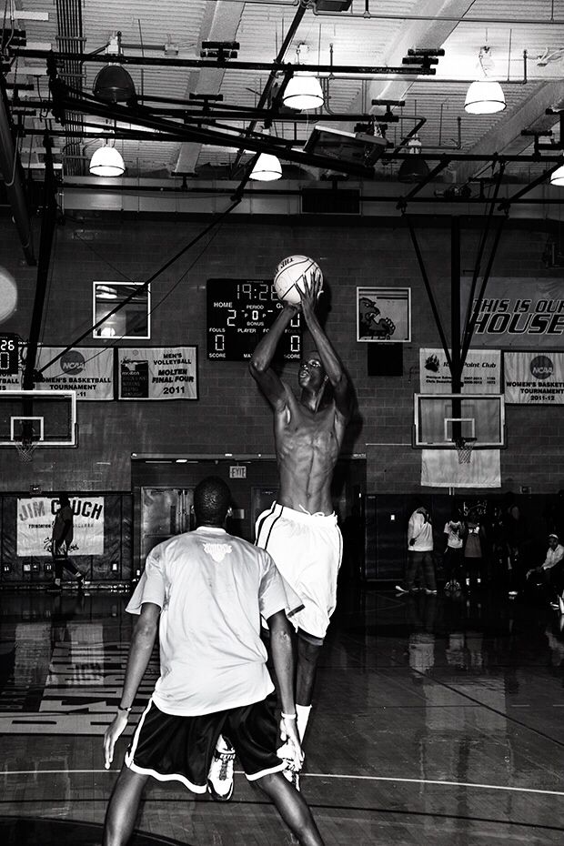 two men playing basketball in an indoor gym