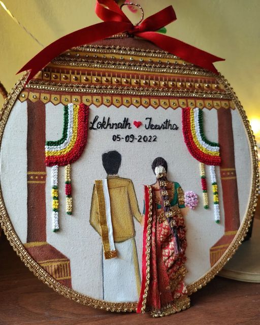 an ornament with two people standing next to each other in front of a red ribbon