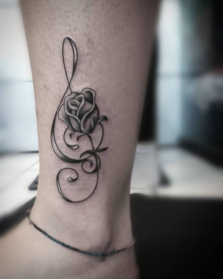 a black and white rose tattoo on the ankle